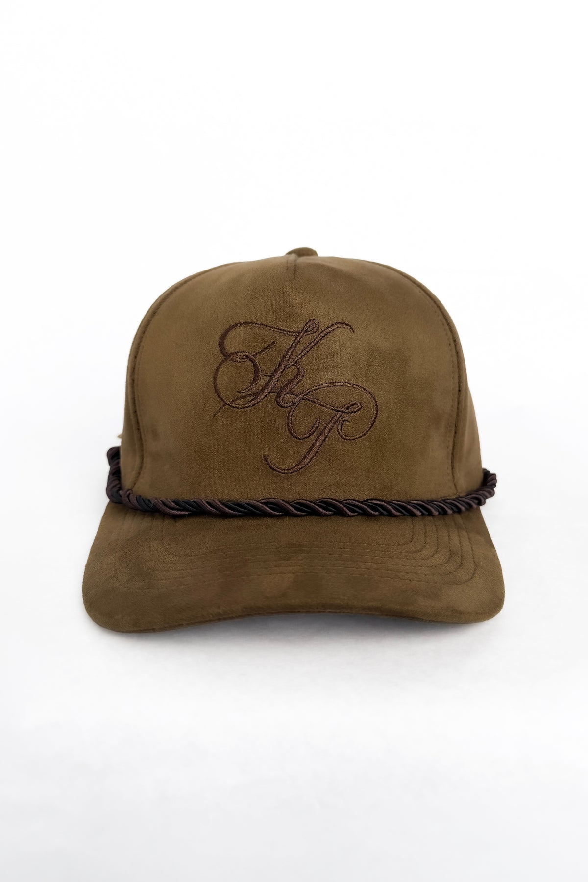 A brown moleskin baseball cap featuring a dark brown embroidered monogram logo on the front and a braided dark brown rope detail wrapped around the base of the crown, shown against a plain white background.