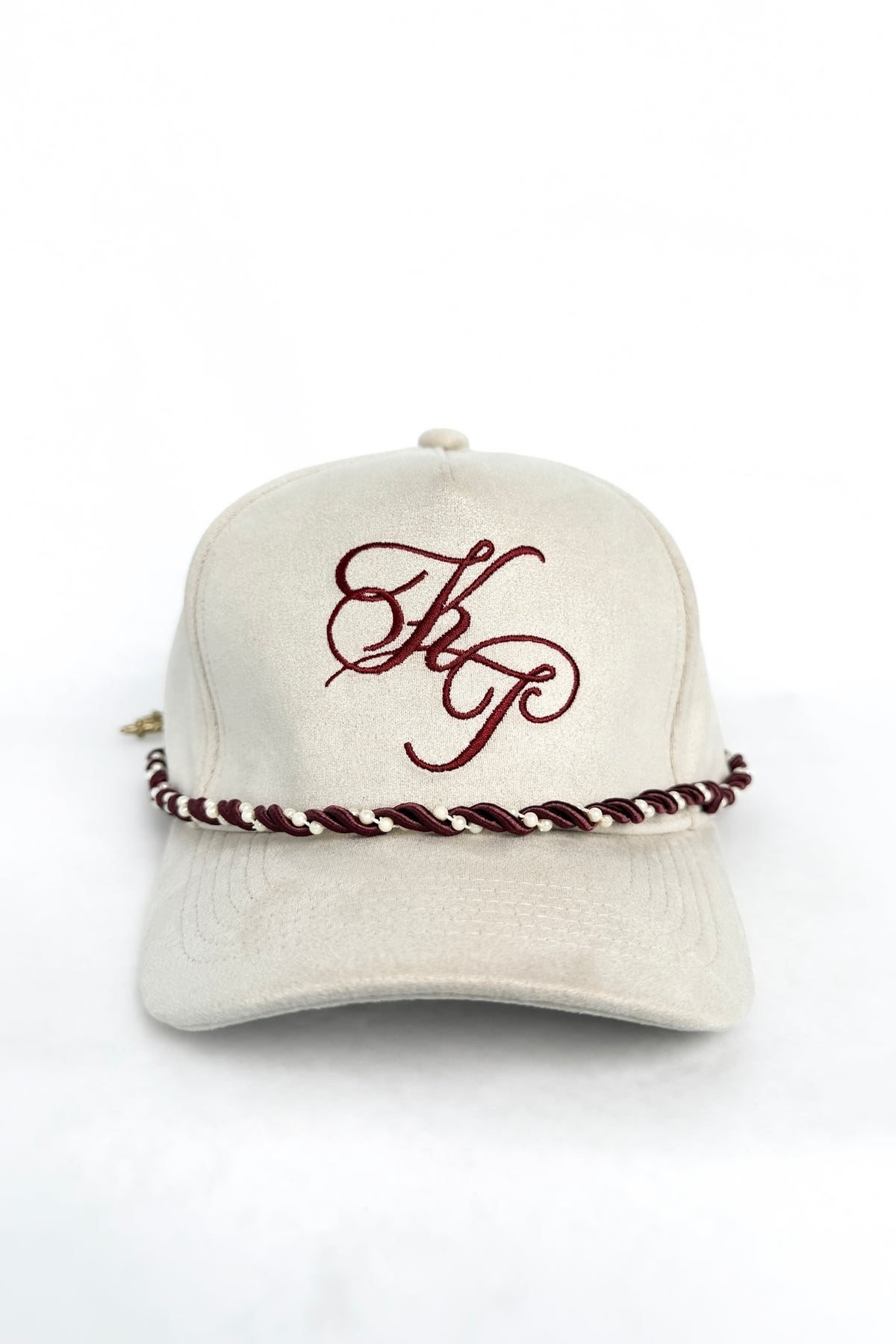 An ivory baseball cap featuring a maroon embroidered monogram on the front and a matching maroon and off-white braided rope detail wrapped around the base of the crown, shown against a plain white background.